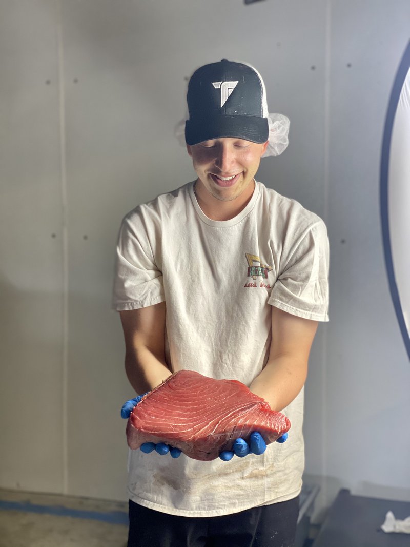 A man in a white shirt admires a cut of bluefin tuna.