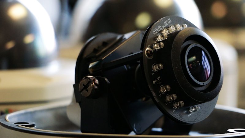 A black camera with a large, round, circular lens surrounded by LED lights