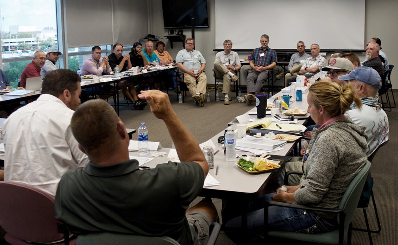 People sit around a rectangle of tables in a large room.