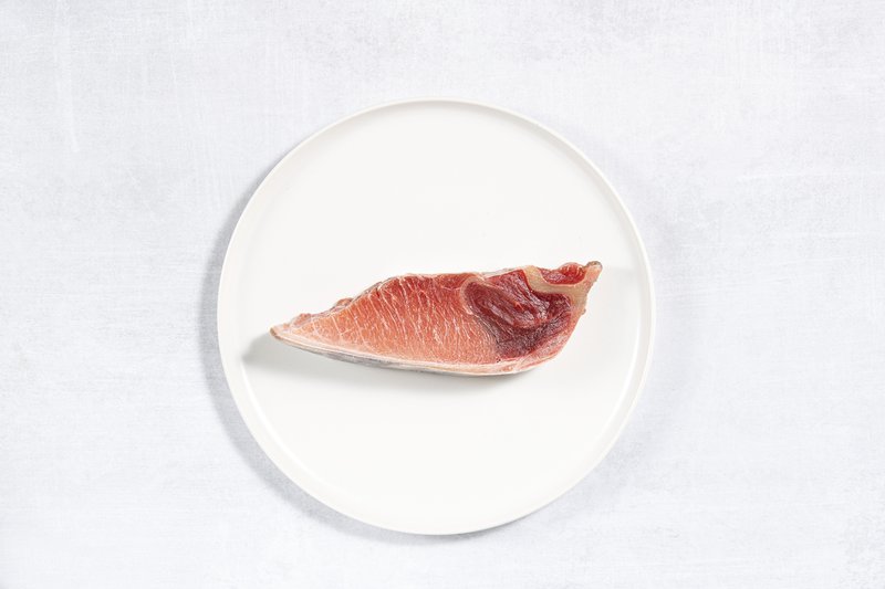 A red cut of tuna sits centered on a white plate.