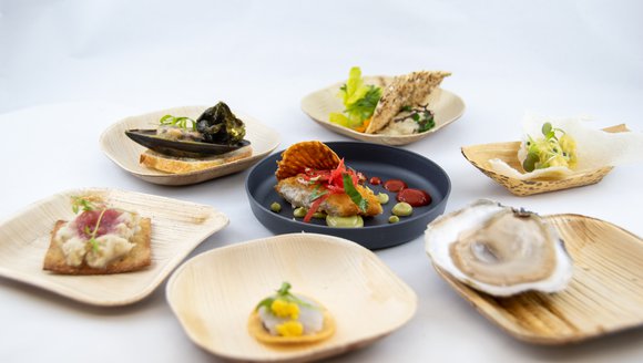 This image shows a range of different seafood dishes placed in a circle on a white table.