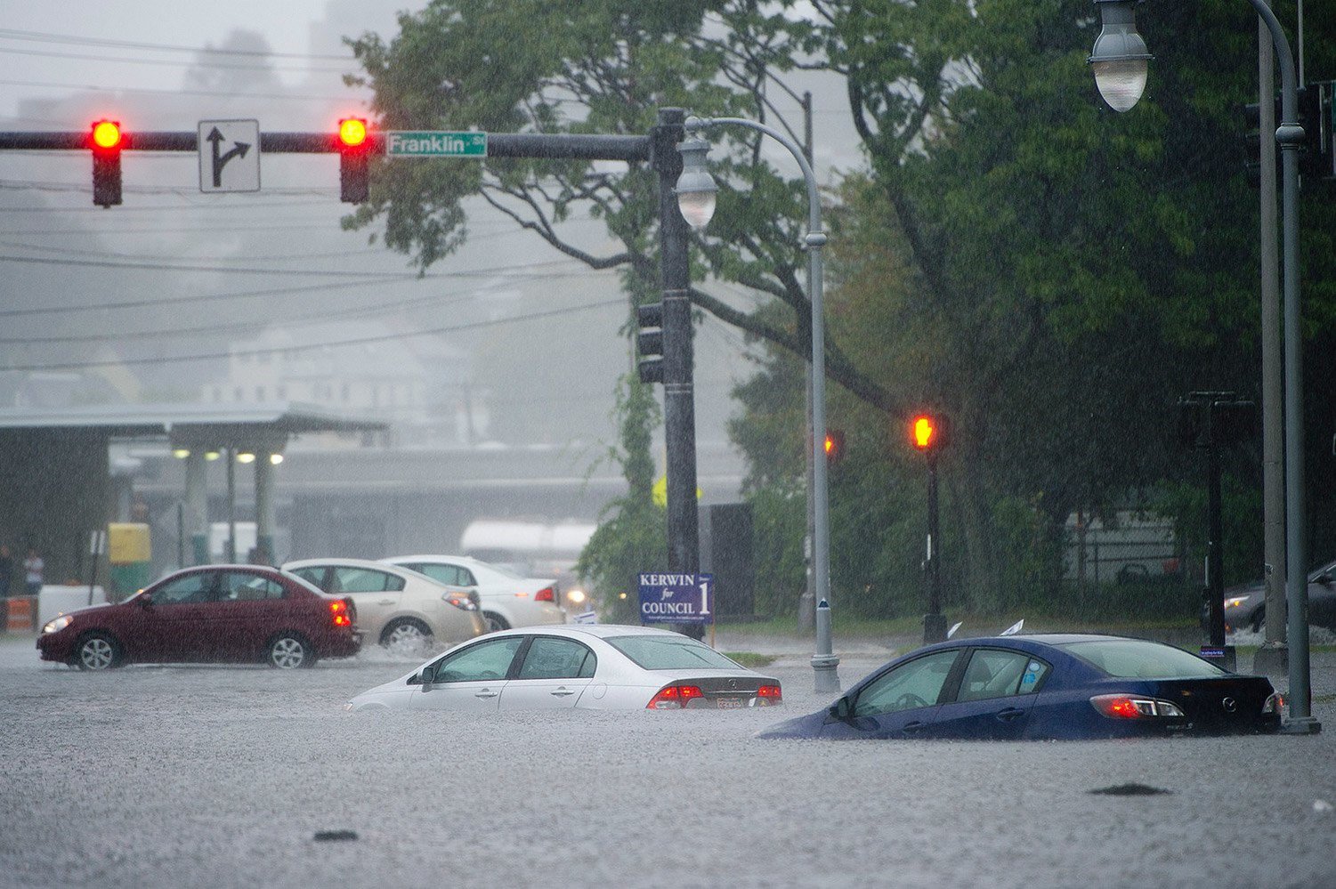 A grey and stormy photo shows several cars submerged in flood waters up to their tailights on Franklin St as heavy downpours soak the area.