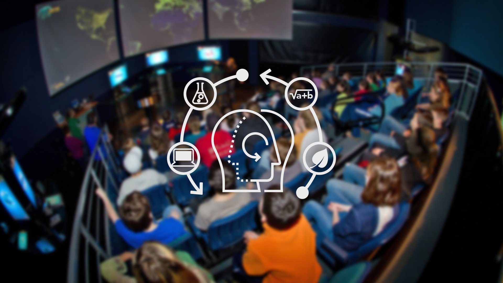 A white graphic with outlines of two human heads, and icons of things like a computer, an equation, and a scientific flask sits centered above a blurry background of students sitting in bleacher rows facing towards a LabVenture educator.