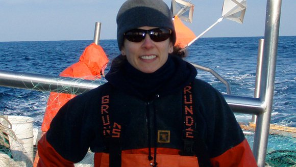 Dr. Lisa Kerr poses for the camera while standing on a boat in sunglasses.