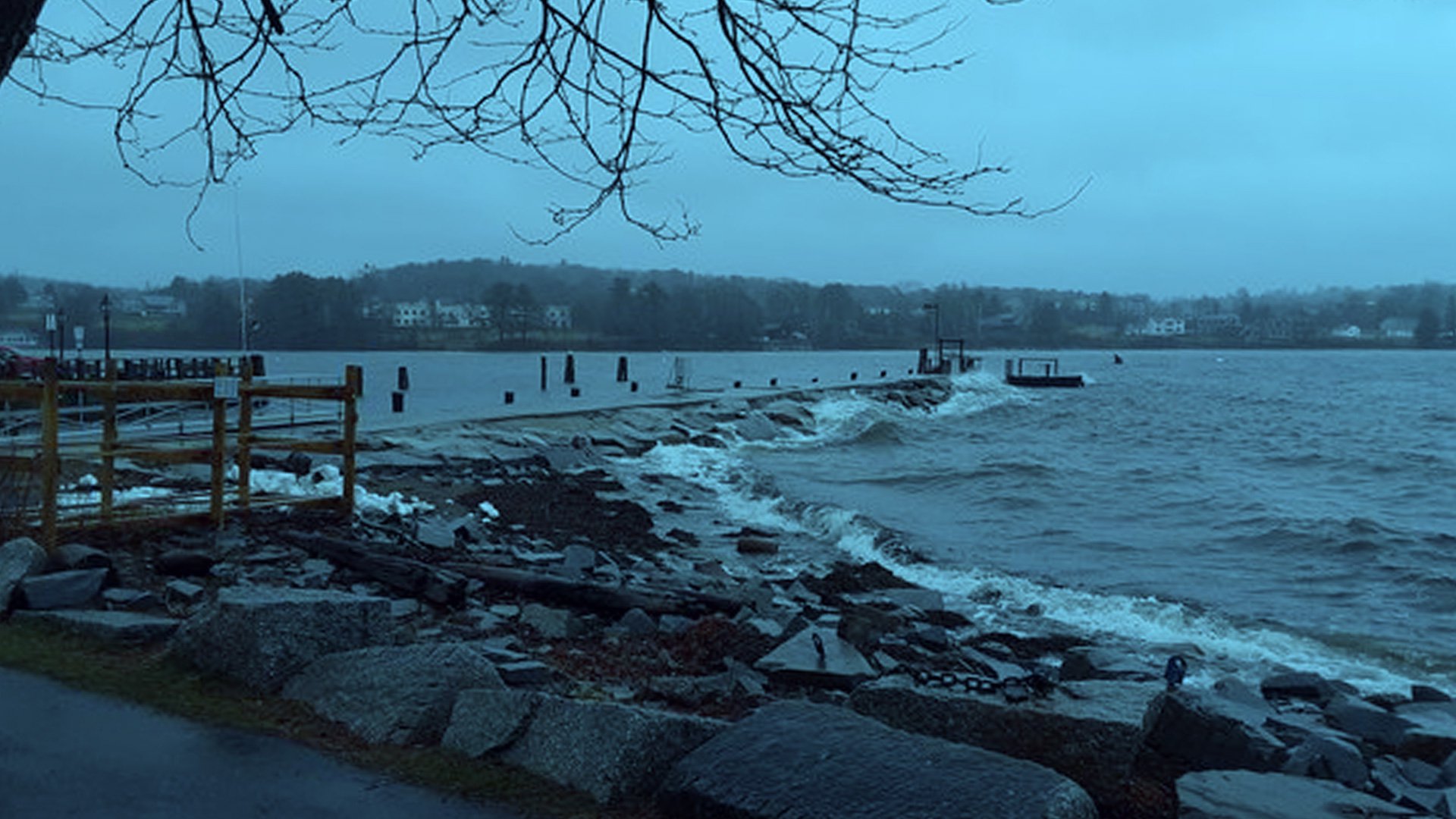 waves crash on a sea wall with a blue filter over the photo